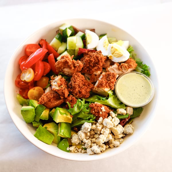 A Frank's Burgers salad with crispy chicken, avocado, tomatoes, blue cheese, and dressing.