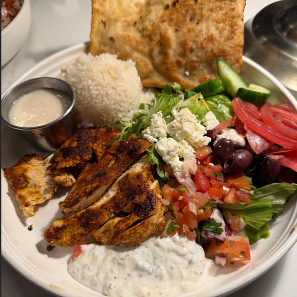 Franks Burgers' grilled chicken plate with rice, salad, feta, olives, pickled onions, and sauces.